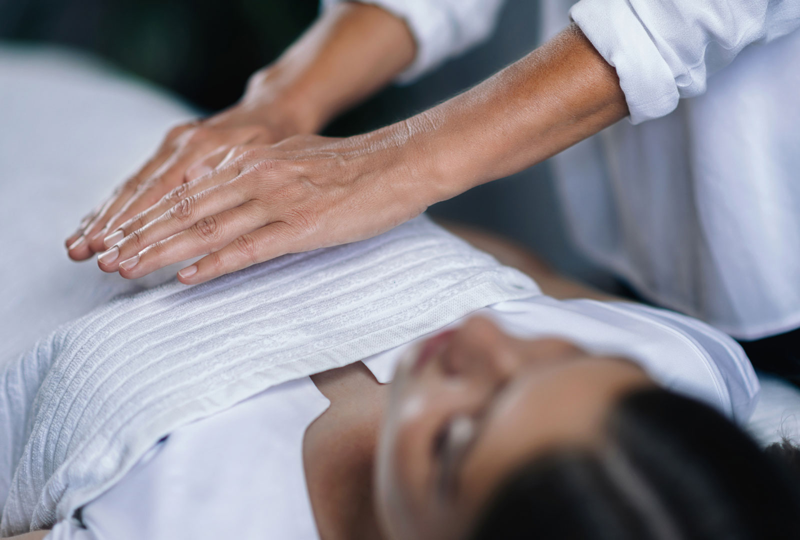 Reiki practitioner places hands over a woman’s body. 