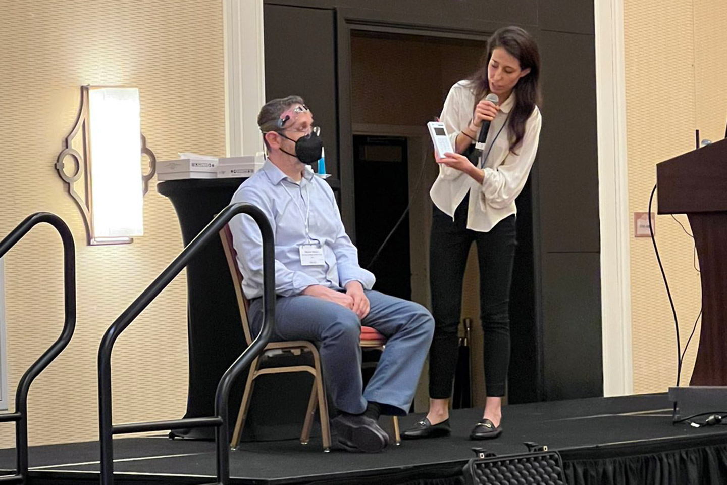 Dr. Giuseppina Pilloni Stands Next to a Man who is Seated and Wears a tDCS Headset