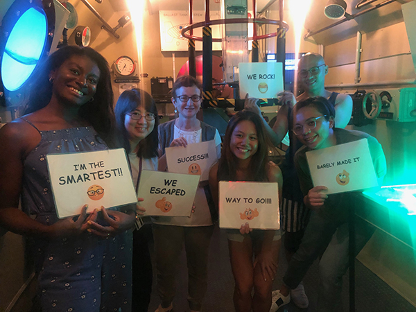 Members of the Treisman Lab Hold Success Signs at an Escape Room
