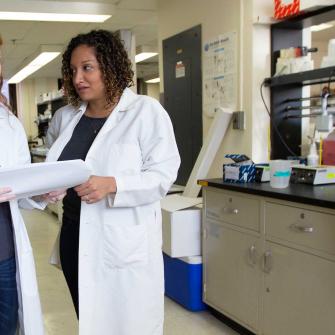 Postdoctoral Fellow Victoria Ruiz Speaks with Colleague in Lab